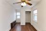 Recessed closet opening, wood-finish flooring, two windows with blinds, and ceiling fan with integrated lighting