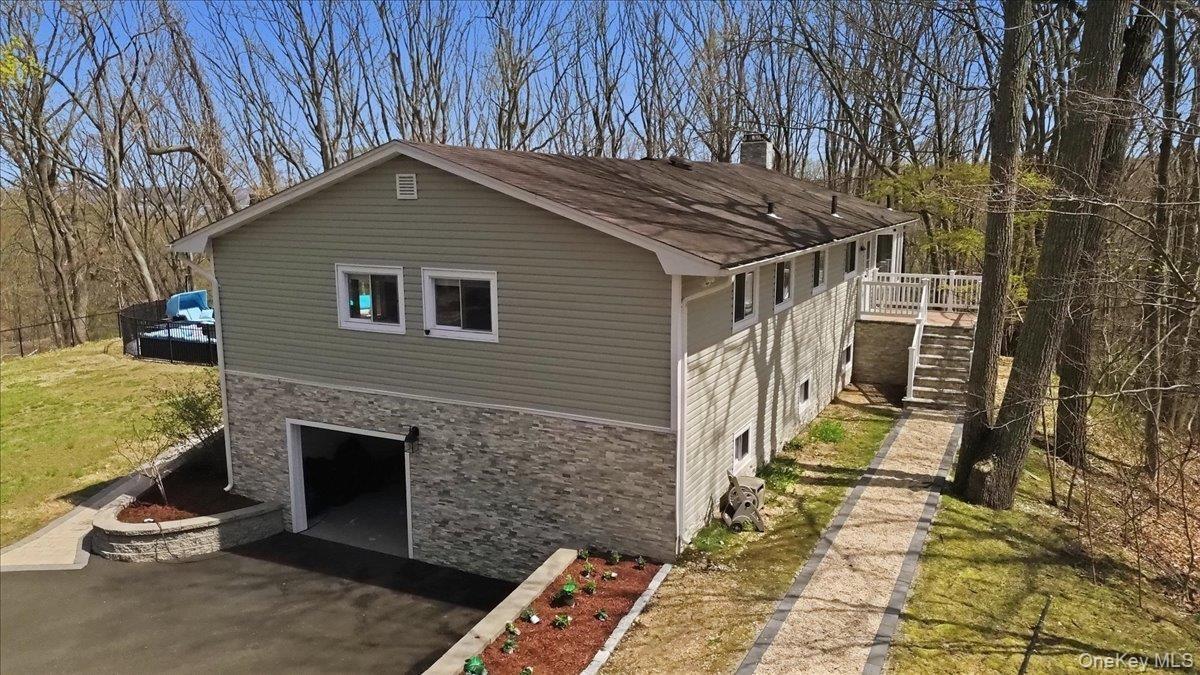 Two-story siding exterior with stone-finish lower level, attached garage, and a raised deck with stairs