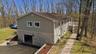 Two-story siding exterior with stone-finish lower level, attached garage, and a raised deck with stairs