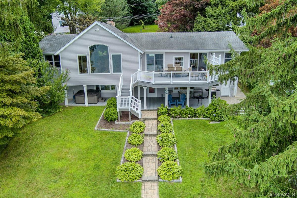 The stunning rear of the home showcases beautiful outdoor living spaces and multiple levels with breathtaking lake views. Lawns for badminton and bocc