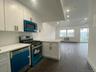 Kitchen with dark hardwood / wood-style flooring, white cabinets, and stainless steel appliances
