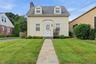 Gable roofline with dormer windows, horizontal siding facade, stone walkway, and a chimney.