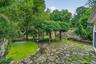 Stone paver patio with natural rock accents, surrounded by mature trees and lush landscaping