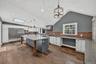 Vaulted ceiling kitchen featuring wood-finish flooring, a skylight, and an expansive island with a stone countertop. Plank Floor, Commercial grade kit