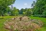 Expansive outdoor area featuring a circular gravel-covered space with tree stump seating and a stone fire pit
