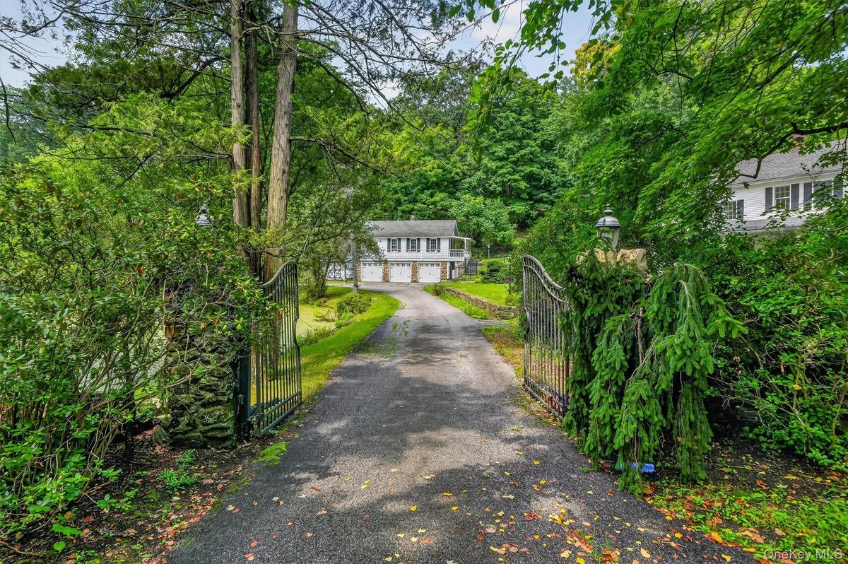 Gated driveway entrance featuring stone pillars with integrated lighting