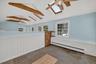 Vaulted ceiling with exposed wood beams, multiple skylights, flagstone flooring, paneled wainscoting, and large windows