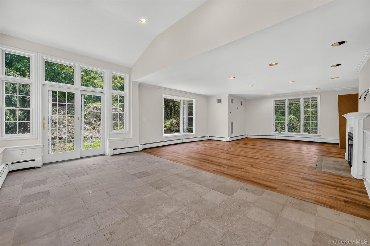 Expansive room featuring wood-finish flooring, a white mantel fireplace, and recessed lighting