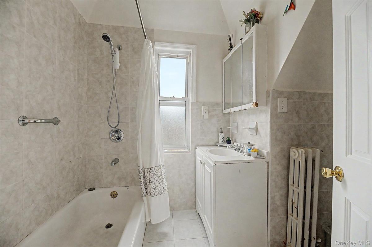 Bright, tiled full bathroom with tub and shower.
