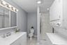 The lower-level full bath features a generous vanity with task lighting, a glass-enclosed shower, and the added convenience of a washer and dryer.