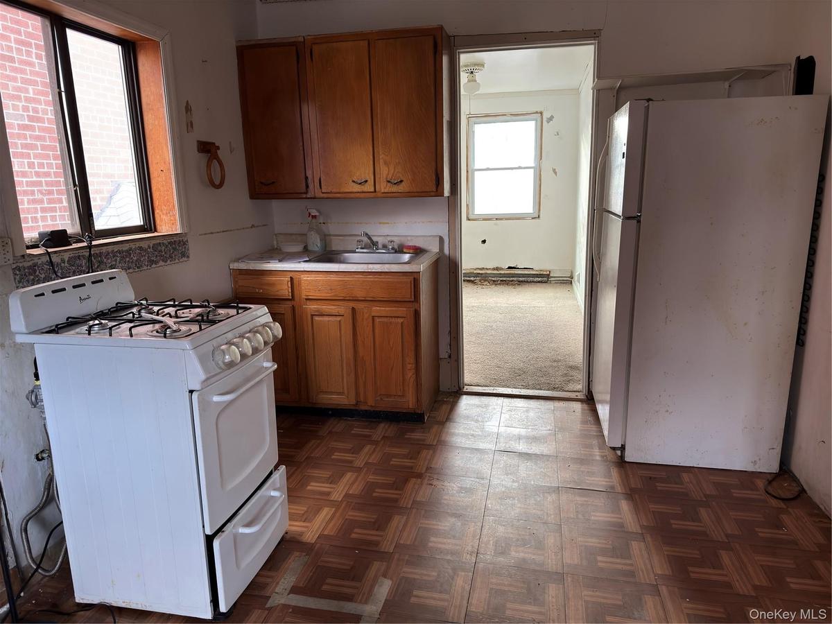 Kitchen featuring white appliances, light countertops, and brown cabinetry