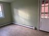 Spare room featuring plenty of natural light, baseboard heating, and carpet