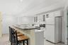 The well-appointed lower-level kitchen features a convenient breakfast bar and brilliant white cabinetry accented with glass-front details, creating a