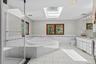 Spacious primary bath featuring a skylight that fills the space with natural light, two separate vanities, and a luxurious soaking tub.