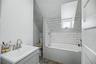 Bathroom featuring a white subway tile surround, built-in bathtub, and a vanity with a brushed nickel faucet