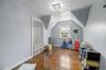 Sloped ceiling room featuring wood-finish flooring, a double window, and a flush-mount light fixture