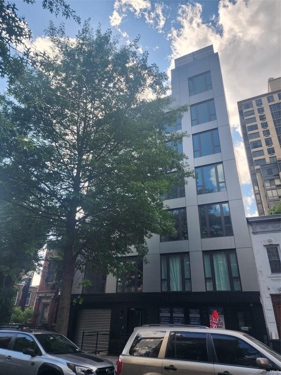 Modern multi-story building featuring a sleek facade, large windows, and a prominent treetop