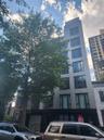 Modern multi-story building featuring a sleek facade, large windows, and a prominent treetop