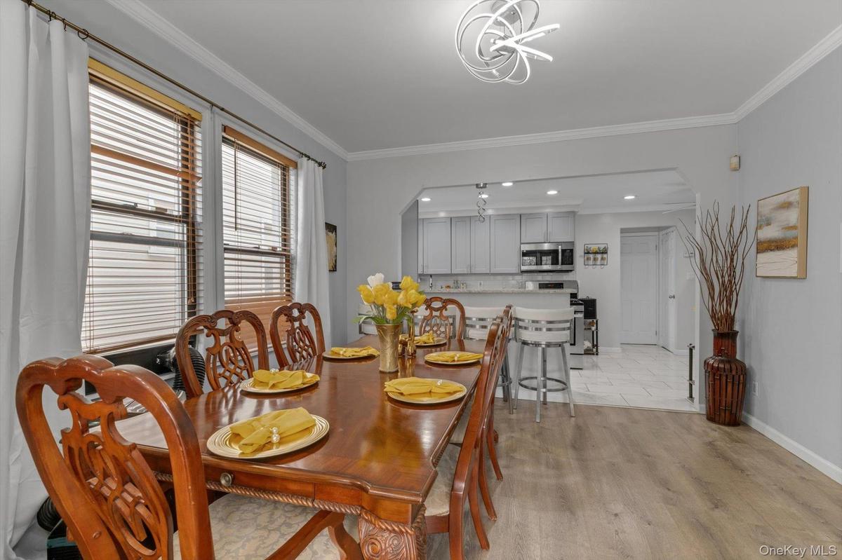 Contemporary light fixtures, crown moldings, kitchen pass-through, and neutral wall tones.