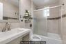 Bathroom featuring a shower-tub combination with sliding frosted glass doors, a vanity with an integrated sink, and tiled walls with a mosaic accent b