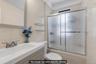 Bathroom featuring a neutral tile shower with sliding glass doors, a vanity with an integrated sink, a framed mirror, and wall-mounted glass shelving.