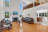 Two-story living area with hardwood flooring, a fireplace featuring a stone surround and hearth, and an upper-level railing overlooking the living roo