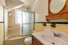 Bathroom featuring a built-in tub with a sliding glass enclosure, a vanity with an integrated sink, and a wall-mounted wooden medicine cabinet with an