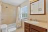 Bathroom featuring a built-in vanity and integrated sink, a tiled shower/tub combination, a window with blinds, and a mirrored medicine cabinet