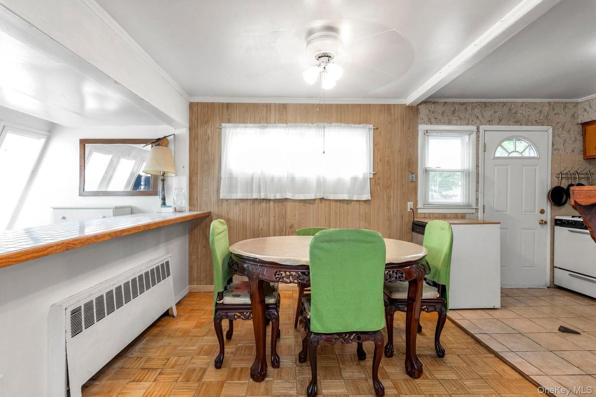 Dining area with wood-finish flooring, wood paneling,  white paneled interior door, and white appliances, dining area