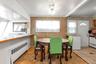 Dining area with wood-finish flooring, wood paneling,  white paneled interior door, and white appliances, dining area