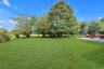 Expansive lawn area with mature trees and a paved patio
