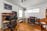 Parquet wood-finish flooring, two window openings, track lighting fixture, and white wall finishes bedroom or office