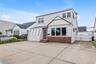 Two-story residence featuring white siding and a brick base, large driveway