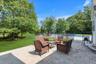 Paved stone patio with a fenced swimming pool, expansive lawn, and mature trees