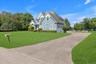 Shingle-sided exterior with multiple gables, an attached two-car garage, a paved driveway, and a spacious lawn