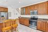 Kitchen featuring stainless steel appliances, wood cabinetry, granite-style countertops, and tile flooring