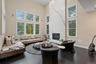 Living room featuring a high ceiling, dark wood-type flooring, and a high end fireplace