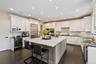 Kitchen with dark stone counters, tasteful backsplash, dark wood-type flooring, white cabinets, and recessed lighting