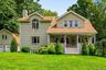 Two-story home with a covered front porch, mature landscaping, and a spacious front lawn.