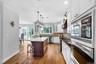 Kitchen featuring wood-finish flooring, white cabinetry, a dark wood-finish island with a light-toned countertop, and stainless steel built-in applian