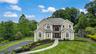 Stately two-story Colonial with cream exterior and dark roof, featuring a symmetrical facade with multiple arched and rectangular windows, a centered 