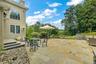 Expansive paver patio with stone retaining walls, stone steps, and a large arched window