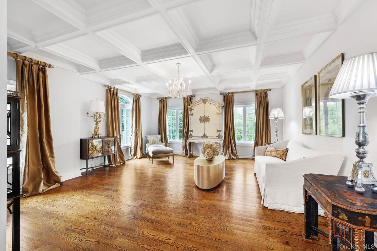 Coffered ceiling with a crystal chandelier, wood-finish flooring, and multiple windows