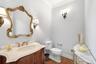 First floor bathroom featuring a wood vanity with a light-toned countertop, an ornate gold-framed mirror, and wood-finish flooring
