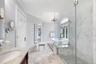 Marble-finish flooring, glass-enclosed shower with tile base, freestanding bathtub, and a double-hung arched window