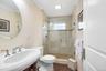 Upstairs elegant bathroom featuring a curved pedestal sink with chrome fixtures, ceramic tile shower enclosure with glass doors, white subway tile sur