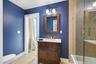 Jack and jill, bathroom hardwood vanity with a light-colored countertop, framed mirror, and a two-light fixture
