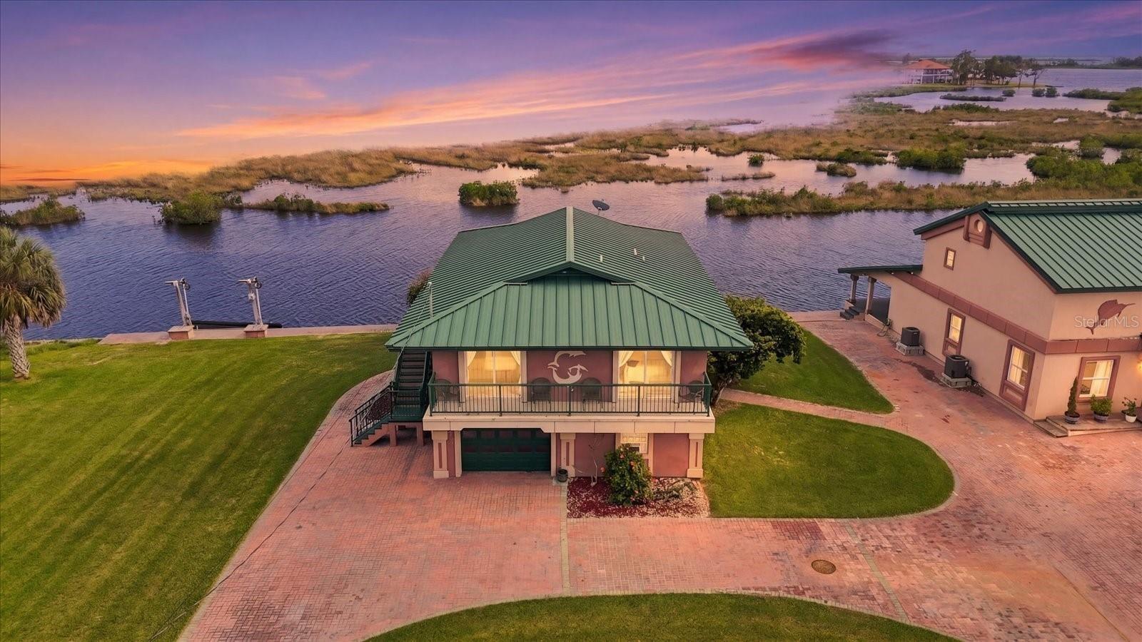 Twilight aerial showcasing the waterfront residence and natural coastal setting.