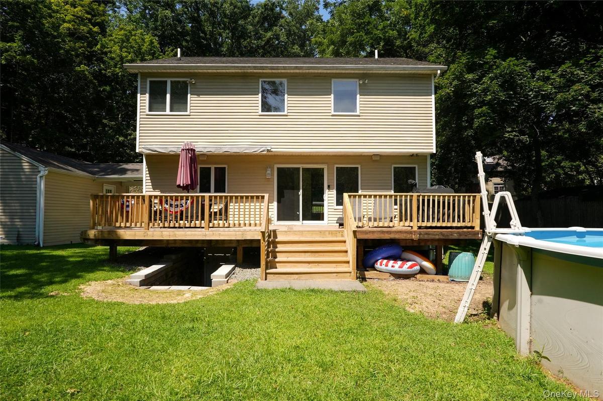 Part of the backyard, new deck with retractable awning, and above-ground swimming pool.