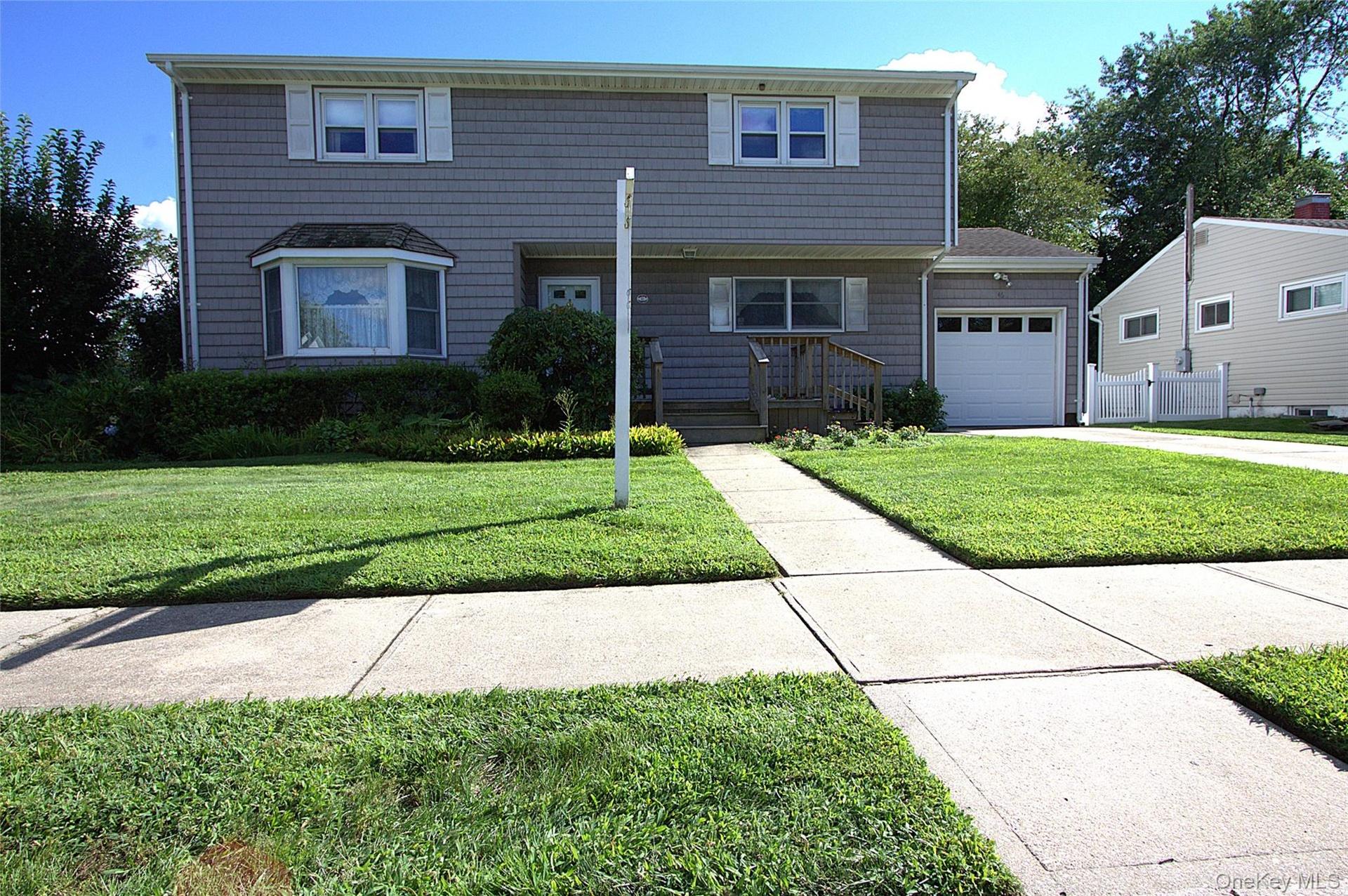Two-story exterior with horizontal siding, a bay window, an attached garage, and a concrete walkway